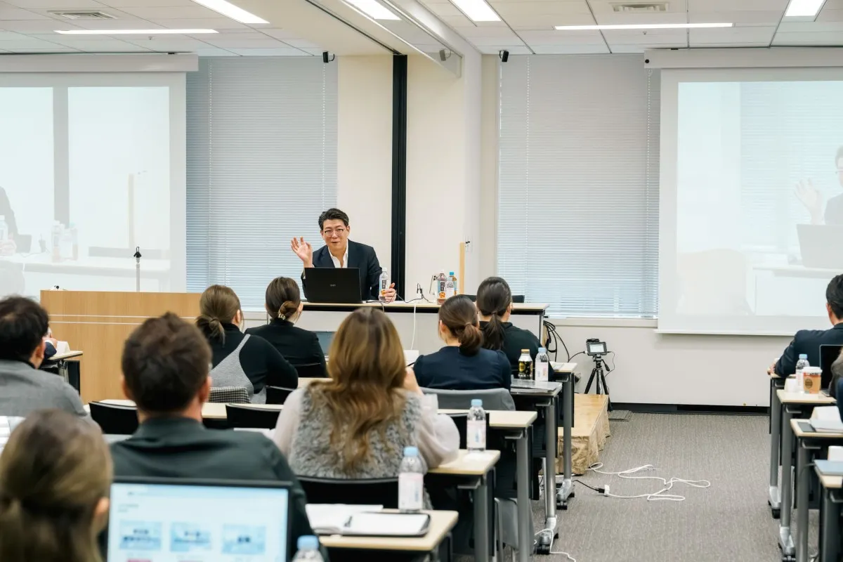 スクリーンの前で講演する講師と受講者
